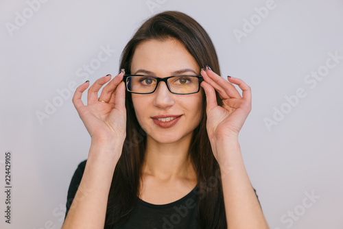 beautiful girl holds a rim of glasses by her both hands and smiles. Close-up