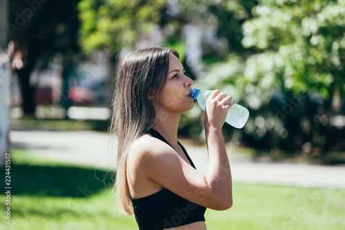 Portrait of fit and sporty young woman drinking water