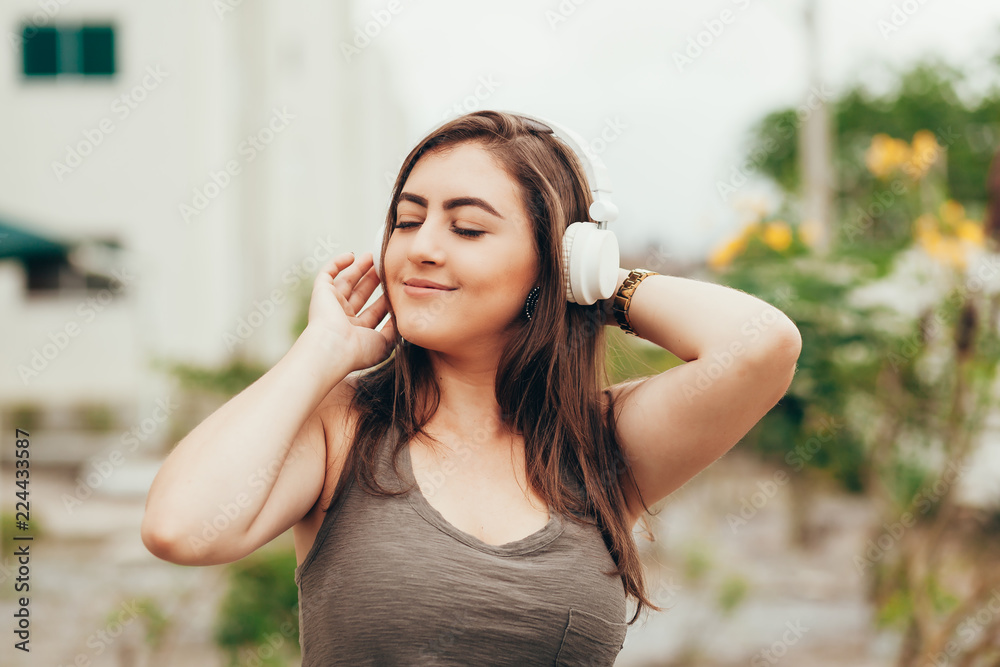 Young woman in the park listening to music on headphones on a sunny day