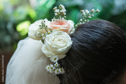 Fashion wedding hairstyle with fresh flowers in veil close up details. 