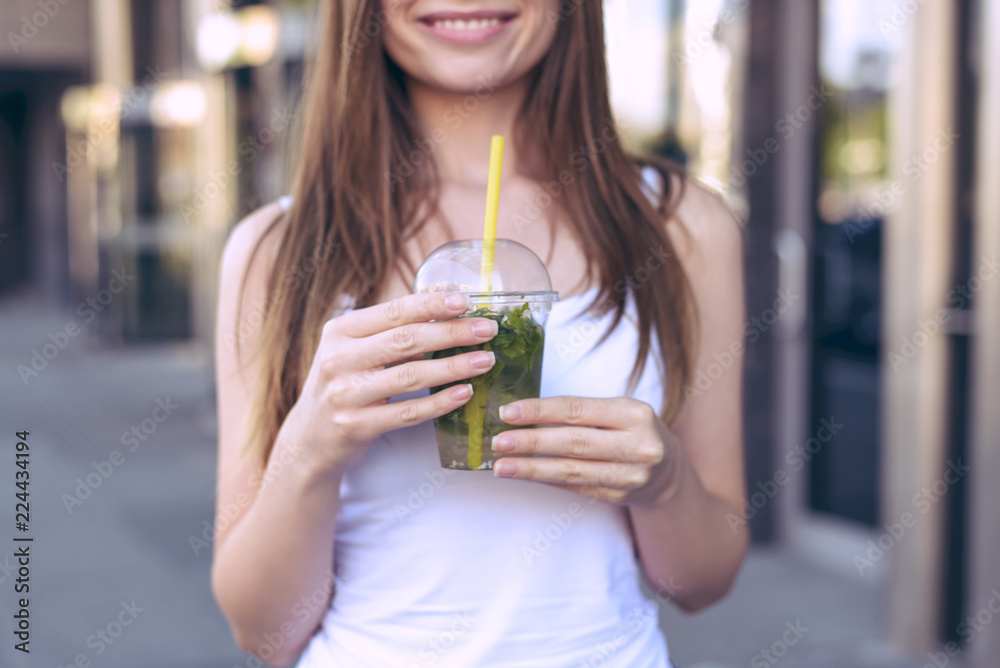 Cropped close up photo of tasty fresh iced cold cool with lemon mint beverage with yellow straw in lady's hands wearing white casual outfit clothing Cropped close up photo of tasty fresh iced cold cool with lemon mint beverage with yellow straw in lady's hands wearing white casual outfit clothing