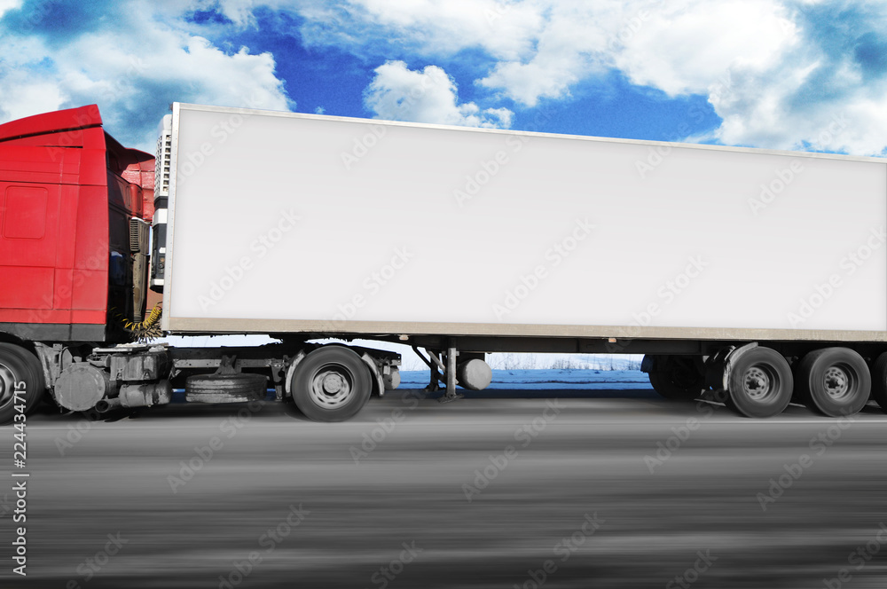 Truck with a trailer driving fast on the winter countryside road with snow against sky with clouds Truck with a trailer driving fast on the winter countryside road with snow against sky with clouds