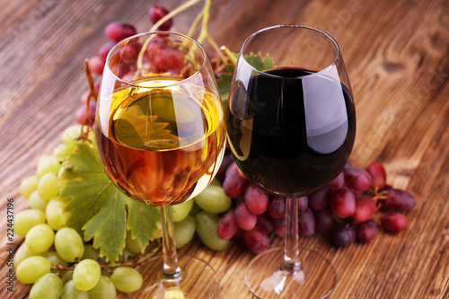 White wine and red wine in a glass with fall grapes on rustic background.
