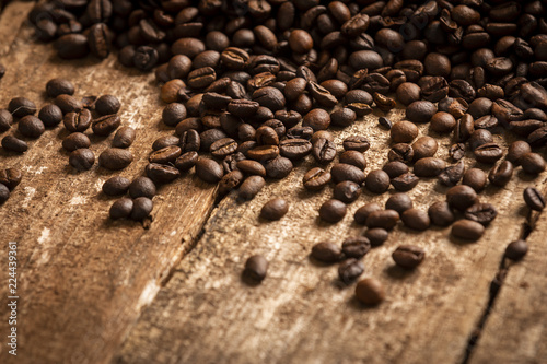 Close-up view of spilled fresh coffee beans on wooden table background