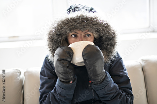 Fotografia Woman have cold drink coffee on the sofa at home with winter coat