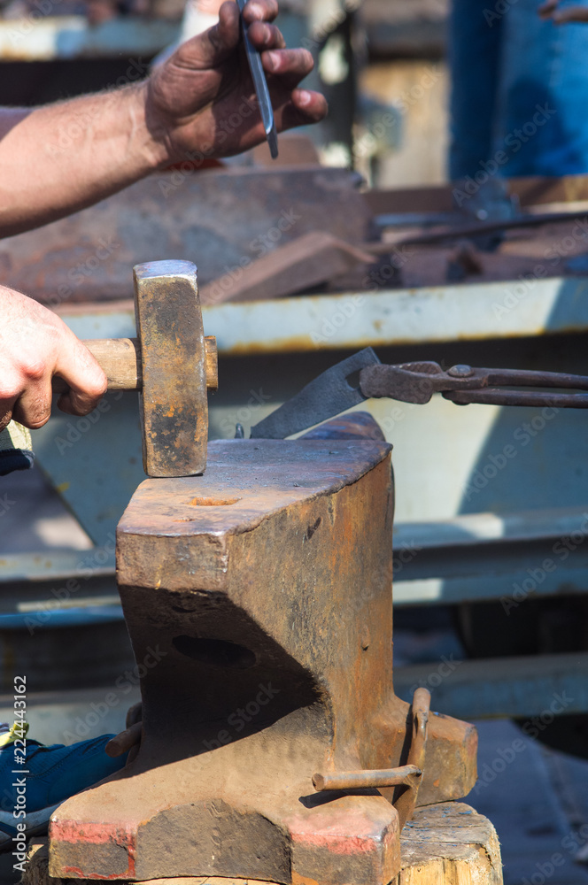 blacksmith performs the forging of hot glowing metal on the anvil blacksmith performs the forging of hot glowing metal on the anvil