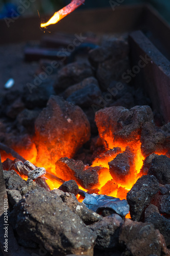 blacksmith furnace with burning coals, tools, and glowing hot metal workpieces