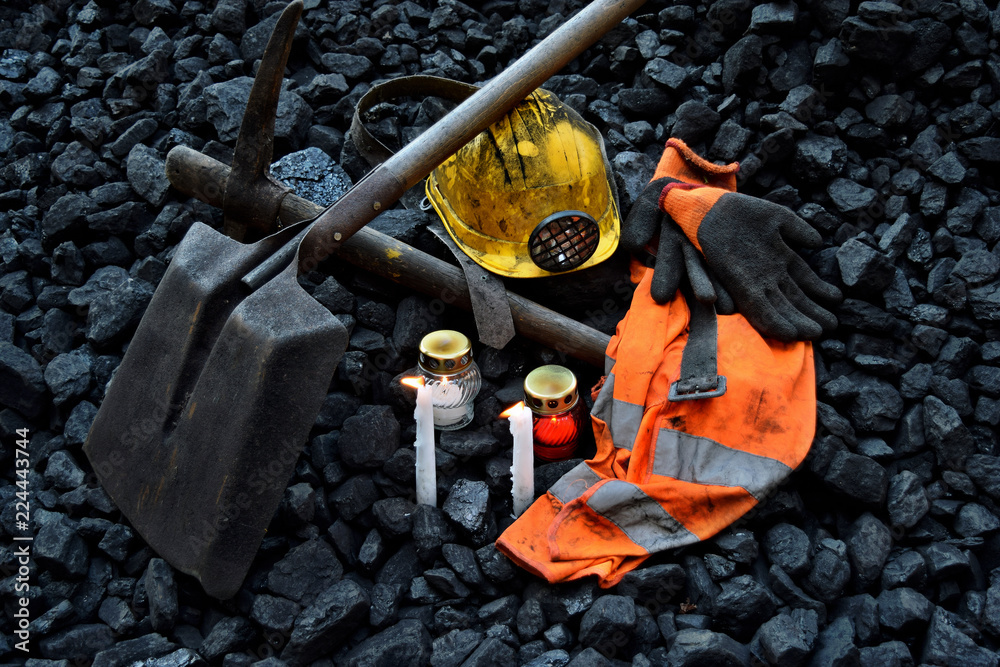 Vigil light, candle with the miner belongings (helmet, gloves, pickaxe, shovel, vest, belt) - obrazy, fototapety, plakaty 