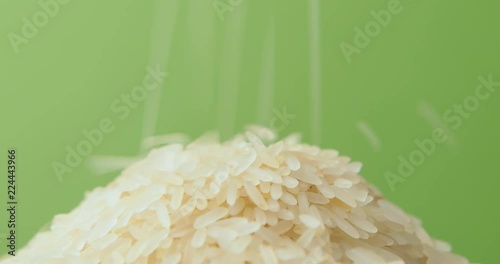 Pouring white rice grains into plate. Pure green background