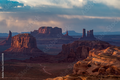 Monument Valley scene - dramatic red rock buttes and mesas kissed with light under dramatic skies 