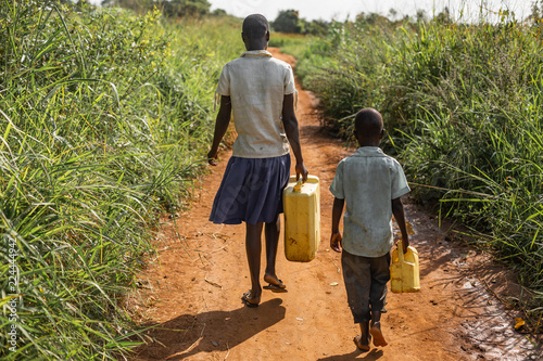 Fotografija Young boy and girl walk to get water for their village, carrying jerry cans