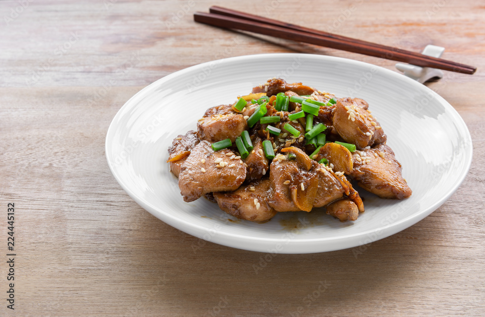stir fried chicken with black soy sauce in a ceramic dish on wooden table. asian homemade style food concept.