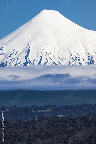 The amazing Osorno Volcano above the waters of Rupanco Lake, the tress inside the forest and the clouds making it an awesome volcanic landscape. It remembers to Mount Fuji. South of Chile photo