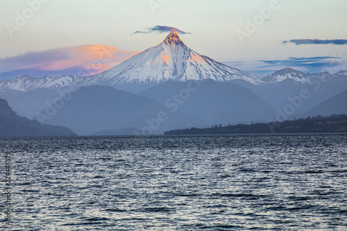 The amazing Puntiagudo Volcano above the waters of Rupanco Lake, the tress inside the forest and the clouds making it an awesome volcanic landscape. A sharpen snow capped summit. South of Chile. photo