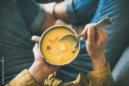 Flat-lay of female sitting keeping mug of Fall warming pumpkin cream soup with croutons top view. Autumn vegetarian, vegan, healthy comfort food eating concept