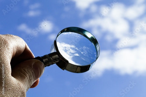 Hand Holding Magnifying Glass On Sky Background Close-up