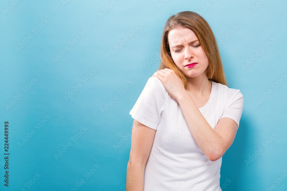 Young woman suffering from neck pain on a blue background Young woman suffering from neck pain on a blue background