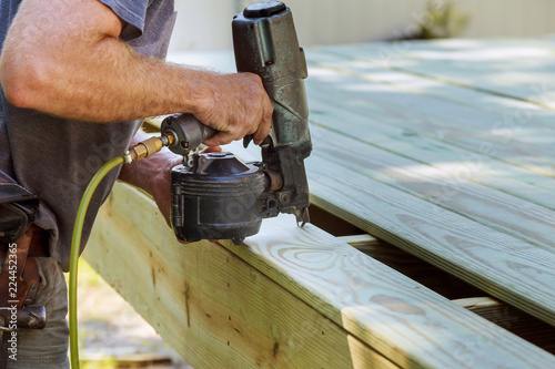 Fotografie Installing Wood on deck, patio construction man using pneumatic gun