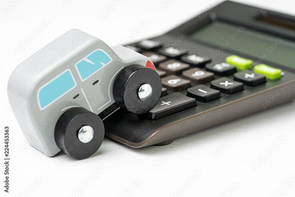 Car maintenance, leasing, loan or insurance money cost and expense calculation concept, miniature cute wooden toy car parking on black calculator on white background Car maintenance, leasing, loan or insurance money cost and expense calculation concept, miniature cute wooden toy car parking on black calculator on white background