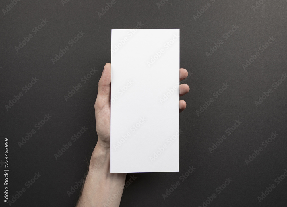 Mens hand holding white flyer Mens hand holding white flyer