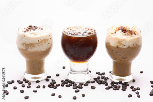 Cold coffee is spilled in clear glass on a white background in the studio.