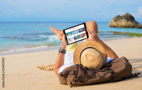 Man reading travel blog on beach