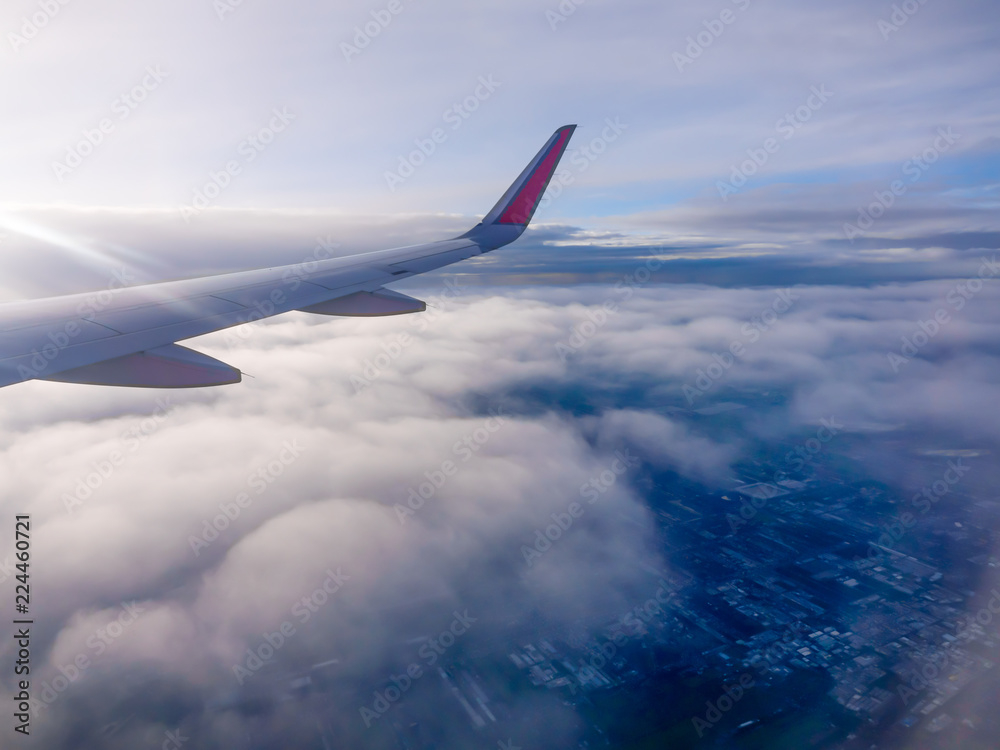 Wing of the plane Fly over the city in Thailand. In the blue sky and white clouds Wing of the plane Fly over the city in Thailand. In the blue sky and white clouds