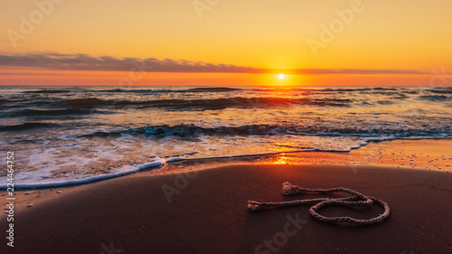A piece of fishing rope on the beach at amazing colorful sunrise