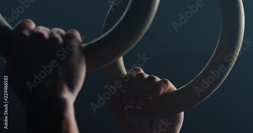 fitness woman training gymnastics exercise using rings enjoying intense muscle workout lifting weight sportswoman bodybuilding olympics practice in gym close up hands slow motion photo