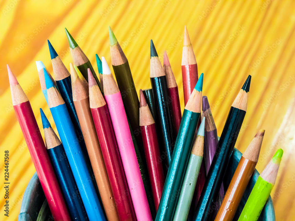 Fototapeta premium Multicolored pencils are combined in a steel box on a desk in the office.