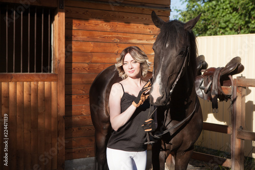 Young beautiful woman next to a horse in a stable