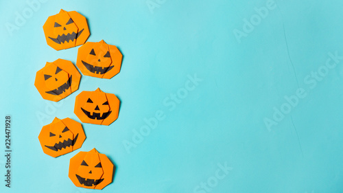 Halloween concept. Paper origami pumpkin on bright blue background. Simple idea for halloween - easy made paper pumpkins on light blue color background. Copy space for text. Banner