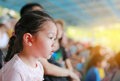 Little Asian child girl watching a show on stadium.
