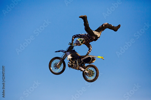 Pro motocross rider riding fmx motorbike, jumping performing extreme stunt. Professional biker jumps photo