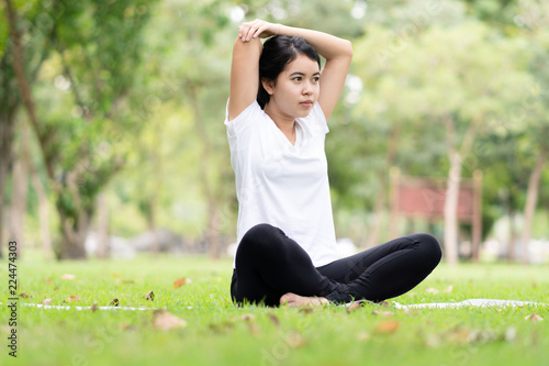 Young woman practicing yoga in the park. © amornchaijj