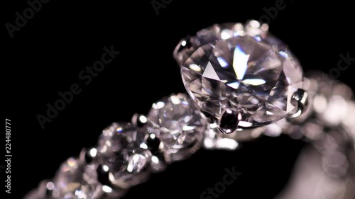 Engagement diamond ring rotating on black background, macro with shallow DoF