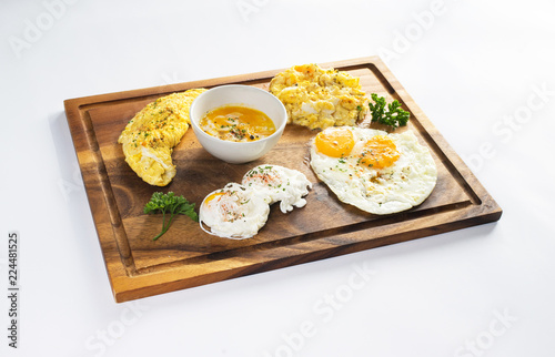 Healthy breakfast with poached egg, scrambled eggs, omelette on wooden plate 