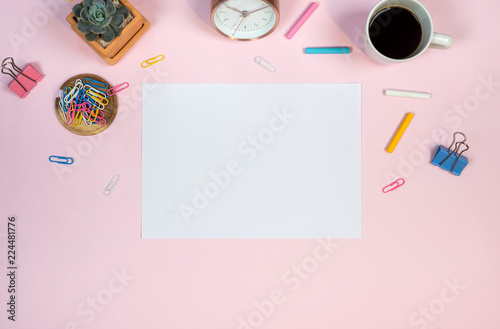 Feminine desk workspace with white paper mockup on pink background. Flat lay, top view.