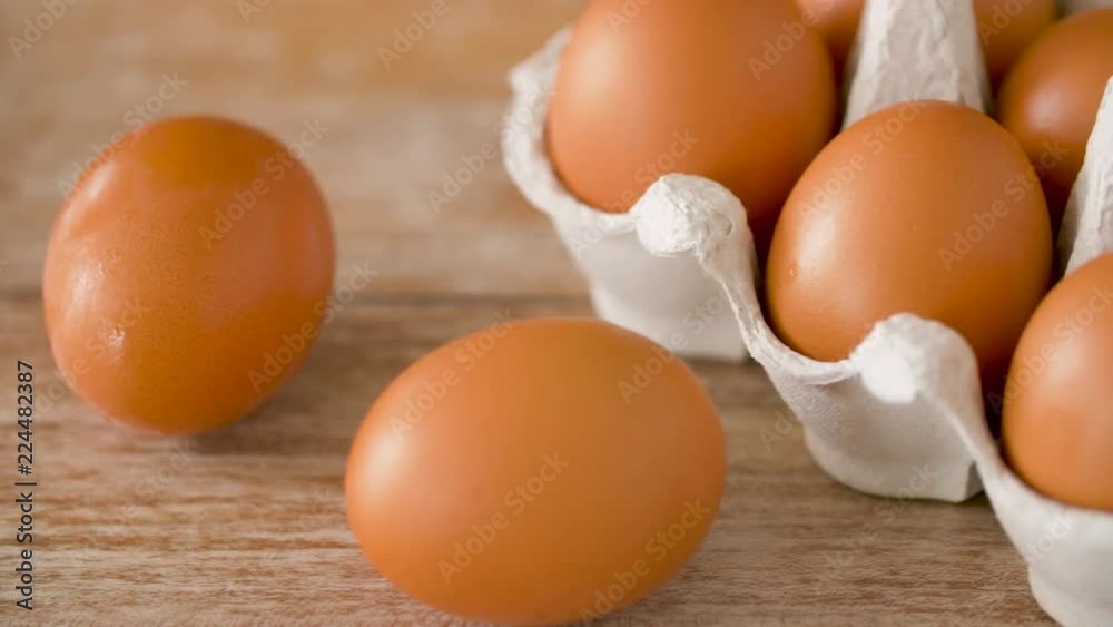 food, culinary and cooking concept - close up of natural chicken eggs in cardboard box on wooden table food, culinary and cooking concept - close up of natural chicken eggs in cardboard box on wooden table