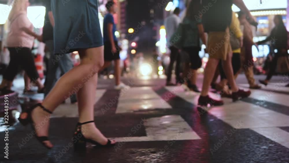 Side view slow motion shot of young businesswoman walking across crowded street at night in Times Square, New York City. Side view slow motion shot of young businesswoman walking across crowded street at night in Times Square, New York City.