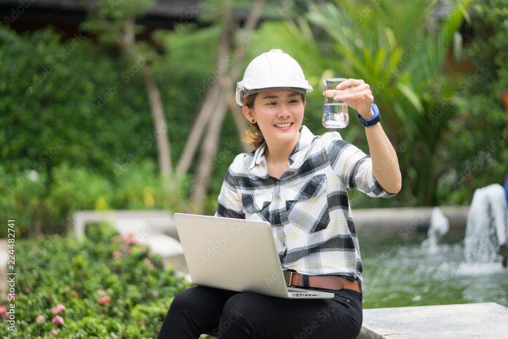 World environment day concept ,Thai Asian Female engineering working with a tablet laptop at sewage treatment plant, engineer controlling the quality of water , aerated activated sludge tank World environment day concept ,Thai Asian Female engineering working with a tablet laptop at sewage treatment plant, engineer controlling the quality of water , aerated activated sludge tank