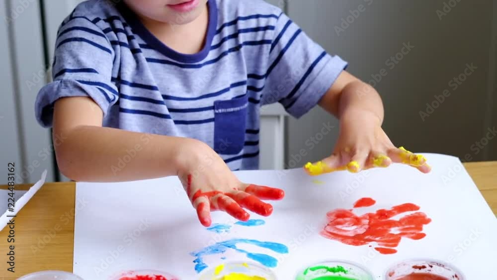 Little boy using finger paints with joy