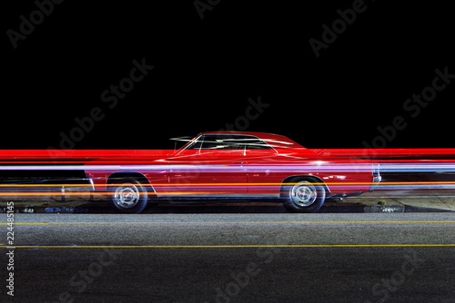 Side view of a vintage classic pick up truck car and light trails caused by traffic in Venice, California at night
