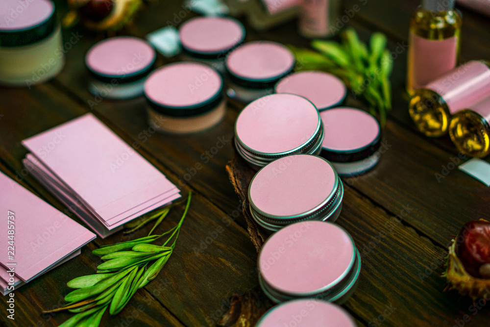 Naklejka premium round jars for cosmetics with a pink sticker on a dark wooden table.