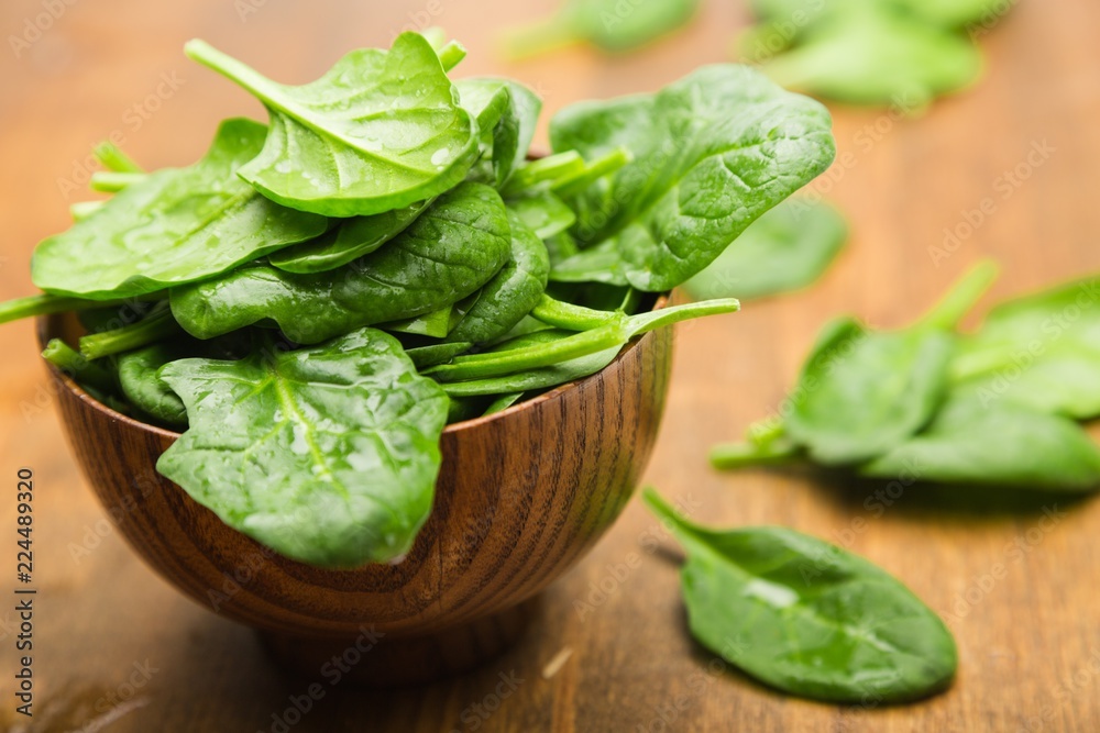 Young Spinach Leaves On Wooden Table And More In Bowl Close-up Young Spinach Leaves On Wooden Table And More In Bowl Close-up