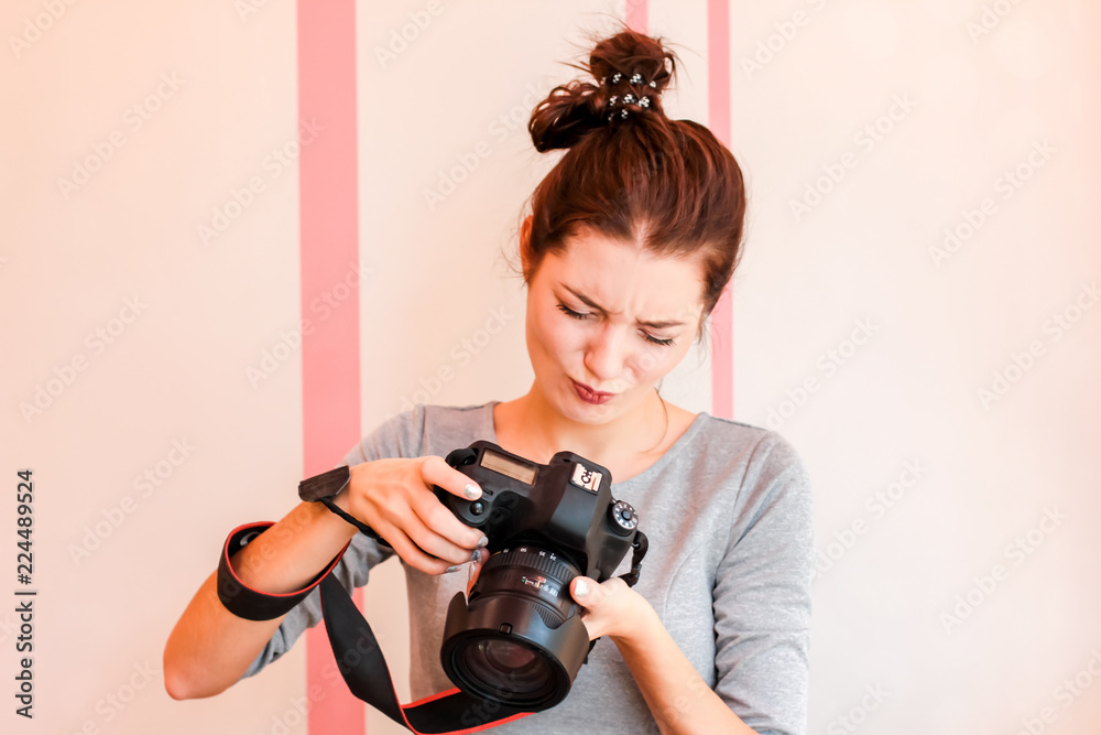 Pretty girl photographer looks into her camera and makes funny d