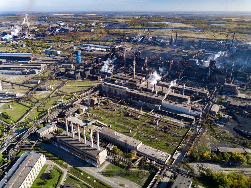 Concept of environmental pollution, drone view of smokestack pipe steel plant, aerial industrial panoramic landscape with blue sky and autumn vegetation, air emissions from manufacturing sector,Russia