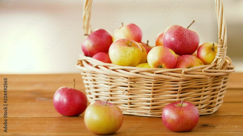 fruits, food and harvest concept - ripe apples in wicker basket on wooden table fruits, food and harvest concept - ripe apples in wicker basket on wooden table