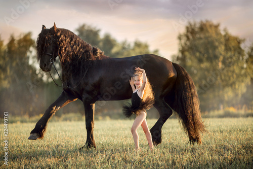 Little ballerina girl with black friesian stallion  photo