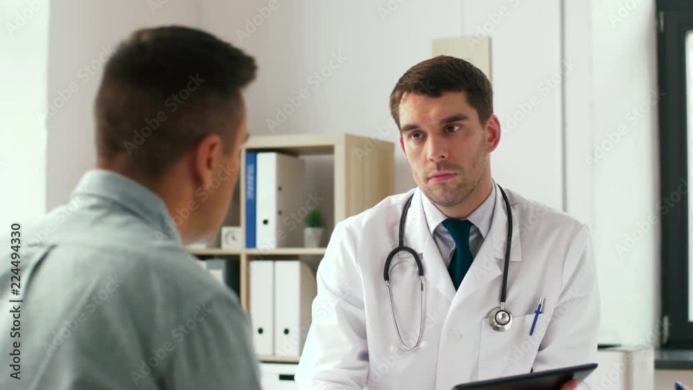 medicine, healthcare and technology concept - doctor with tablet pc computer and male patient talking at hospital medicine, healthcare and technology concept - doctor with tablet pc computer and male patient talking at hospital
